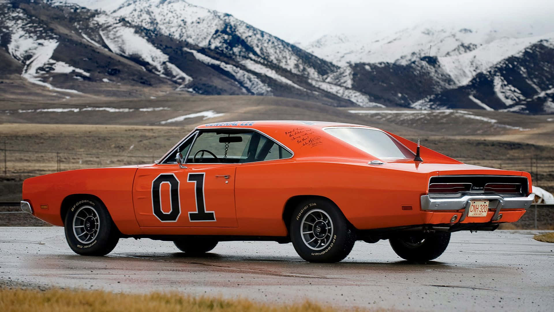 An Orange Dodge Charger Is Driving Down The Road Wallpaper
