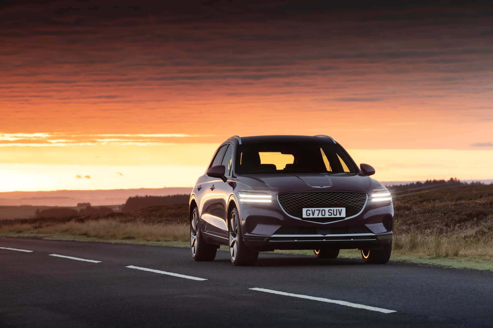 Caption: Sleek Genesis GV70 cruising on a road Wallpaper