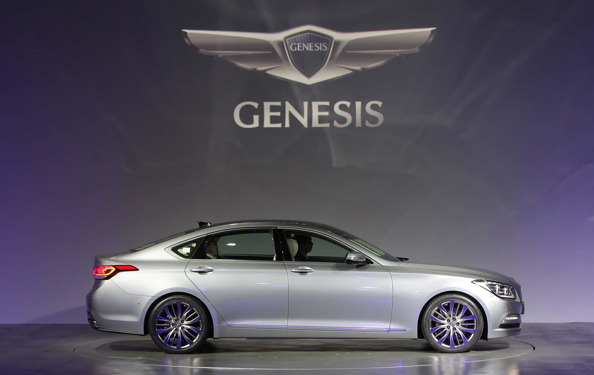 A Silver Genesis Sedan Is On Display At An Auto Show