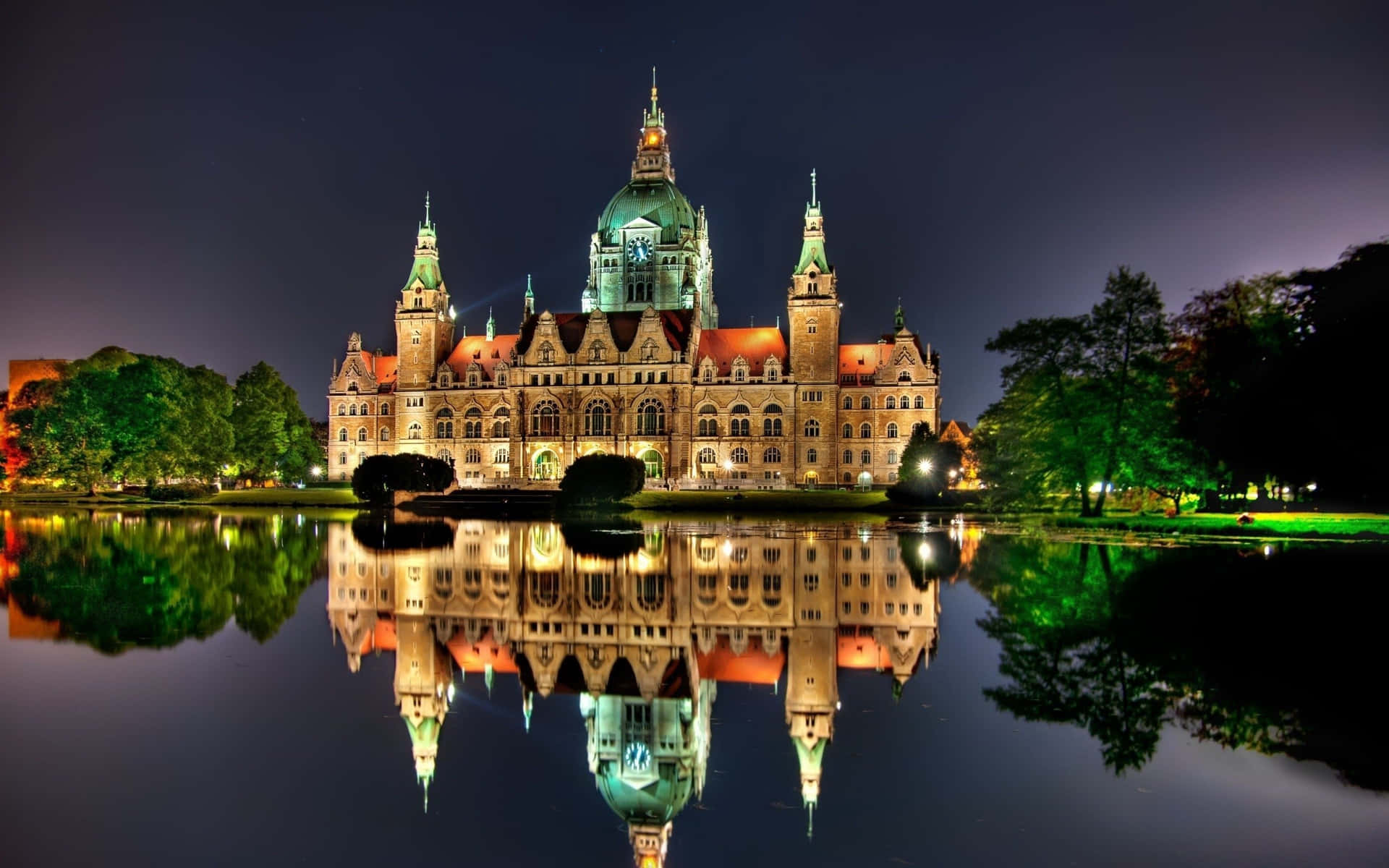 A Large Building Is Reflected In A Lake At Night