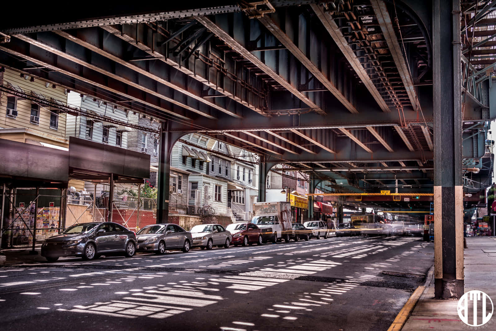 A Street With Cars Parked Under A Bridge Wallpaper