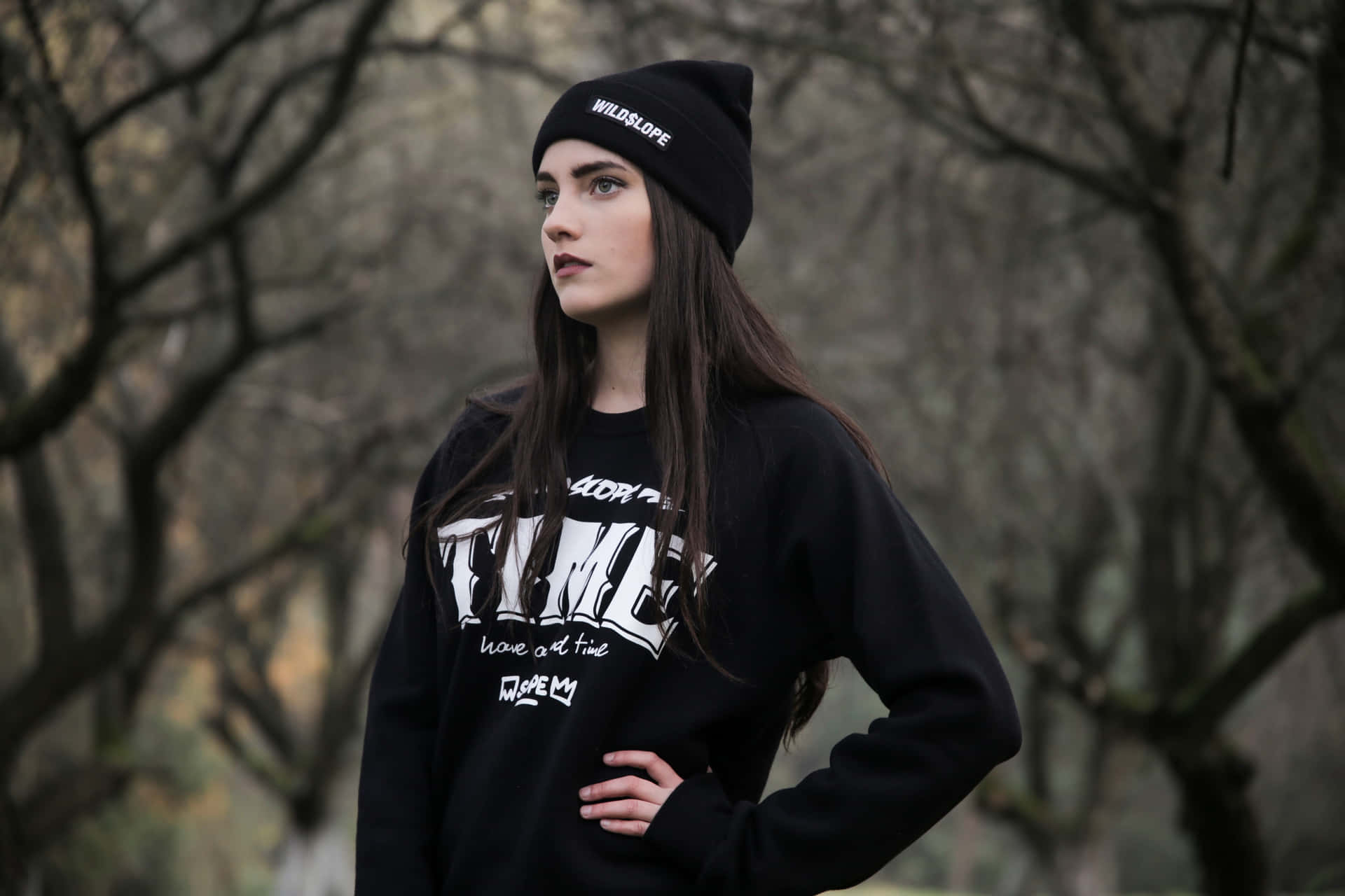 A Young Woman Wearing A Black Sweatshirt And Beanie Wallpaper