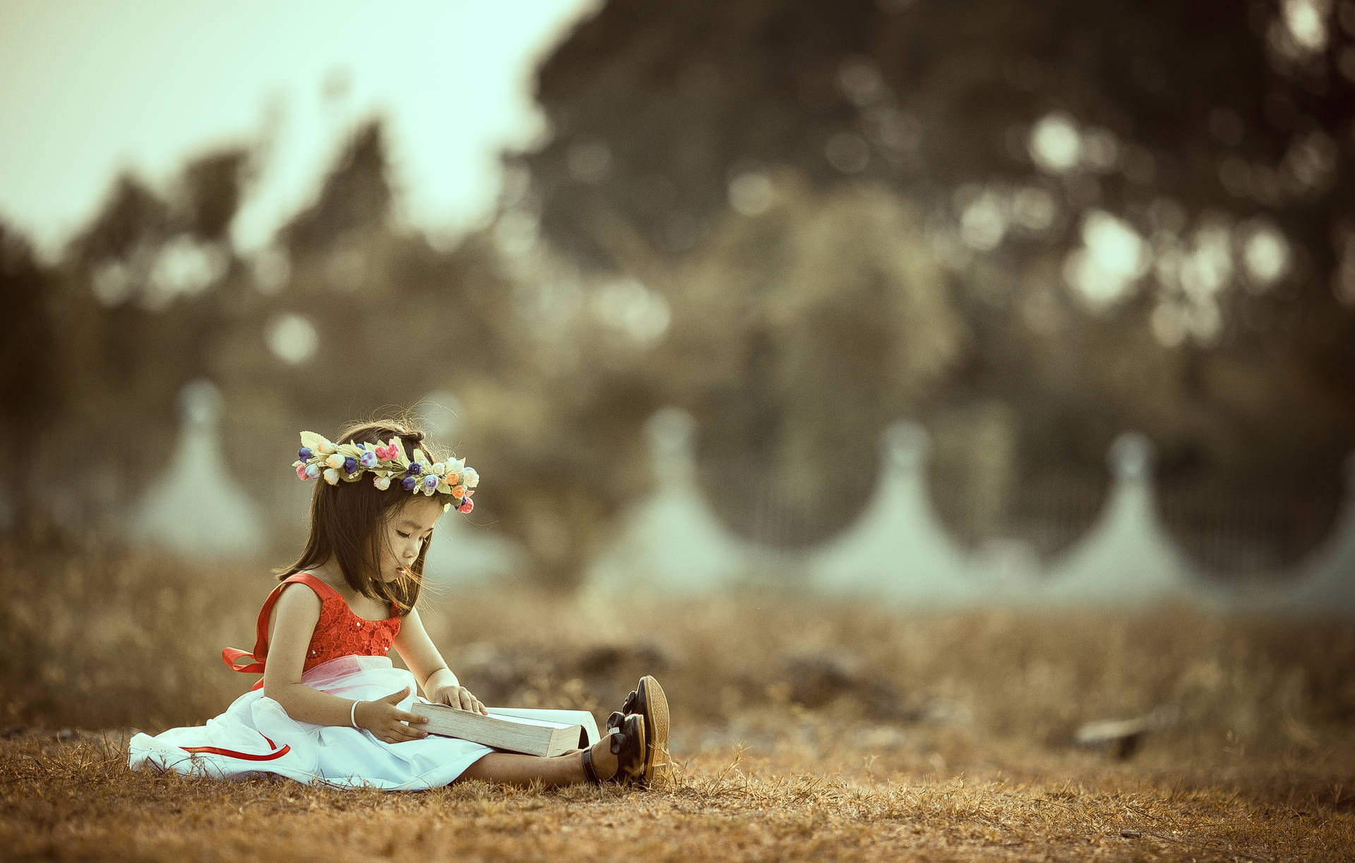 Photo of little girl holding a book in the field wallpaper.