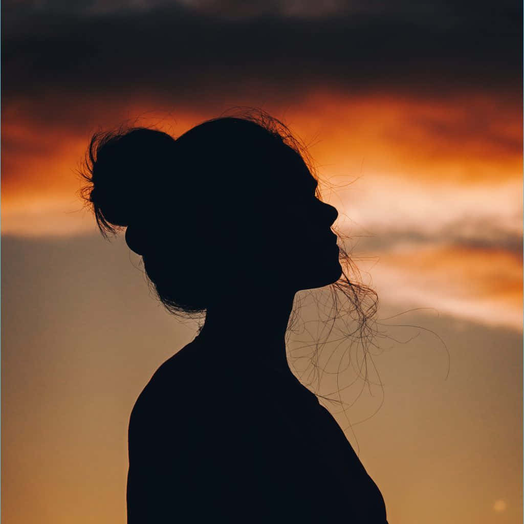 "A beautiful girl standing in the light and shadow of a sunset."