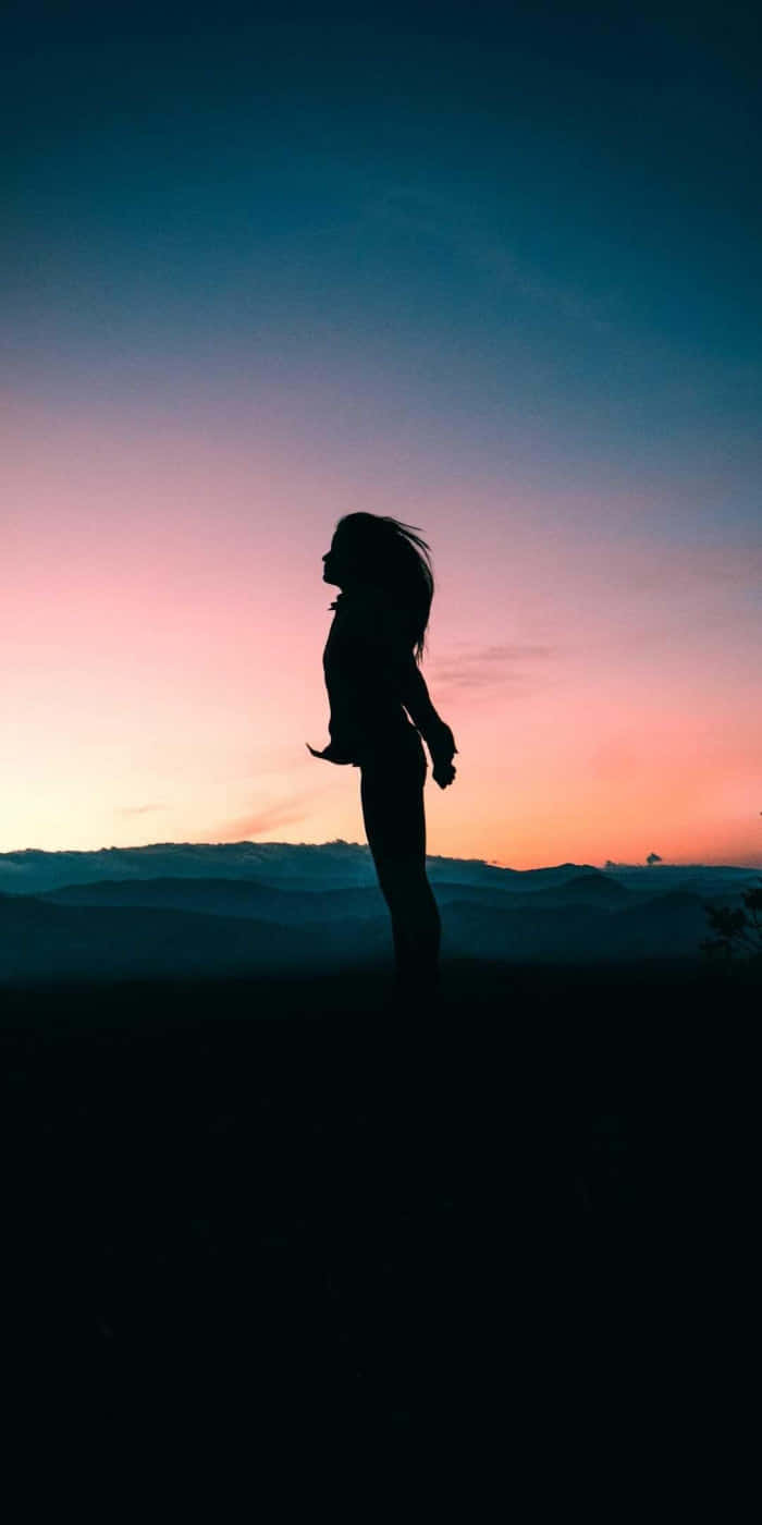 A silhouette of a girl walking in a sunlit road