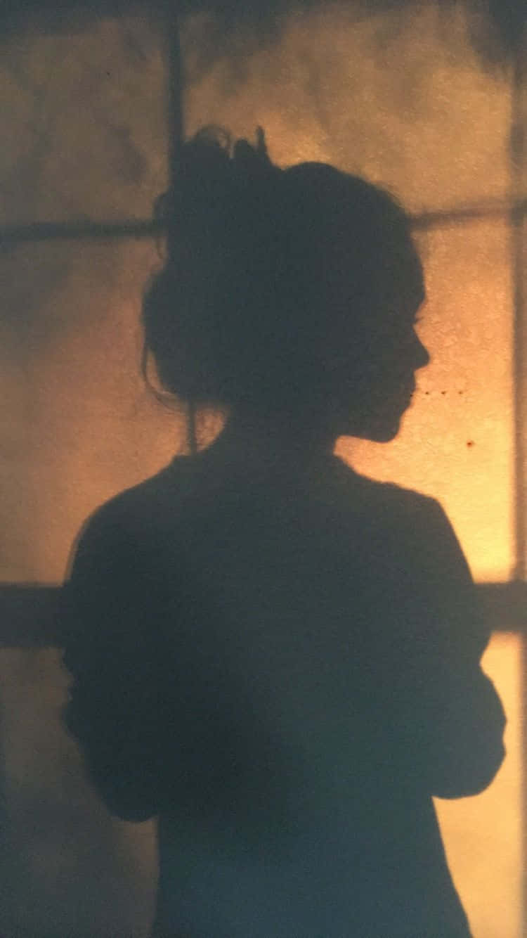 A Silhouette Of A Woman Standing In Front Of A Window