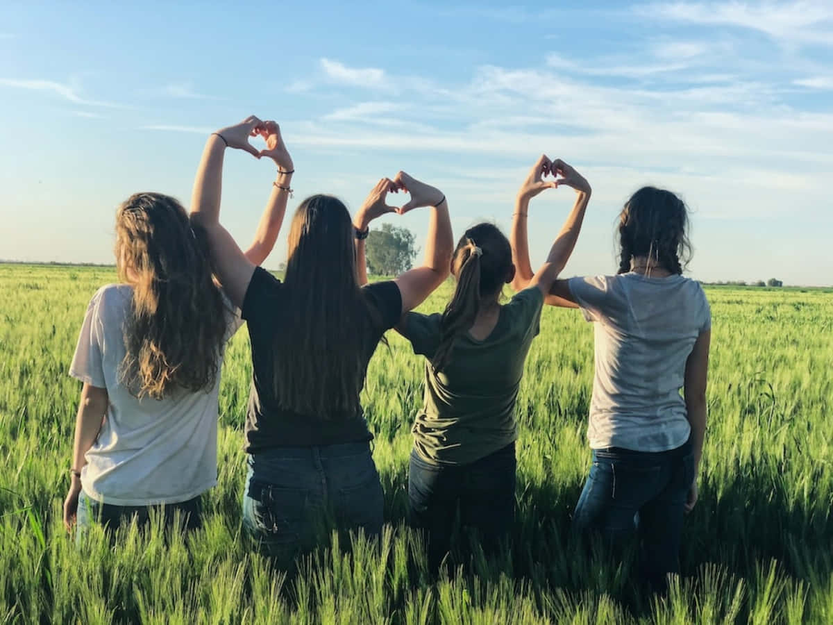 Four Girls Making A Heart Shape In A Wheat Field