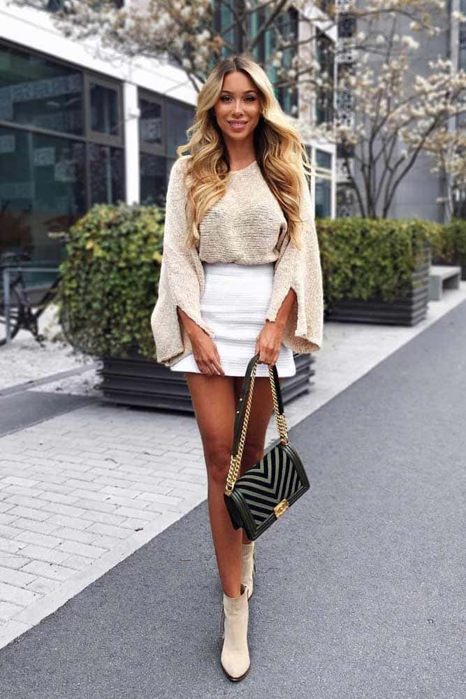 A Woman In A White Skirt And Beige Sweater