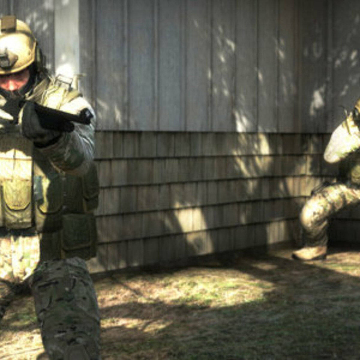 Two Soldiers In Camouflage Are Standing In Front Of A House Wallpaper