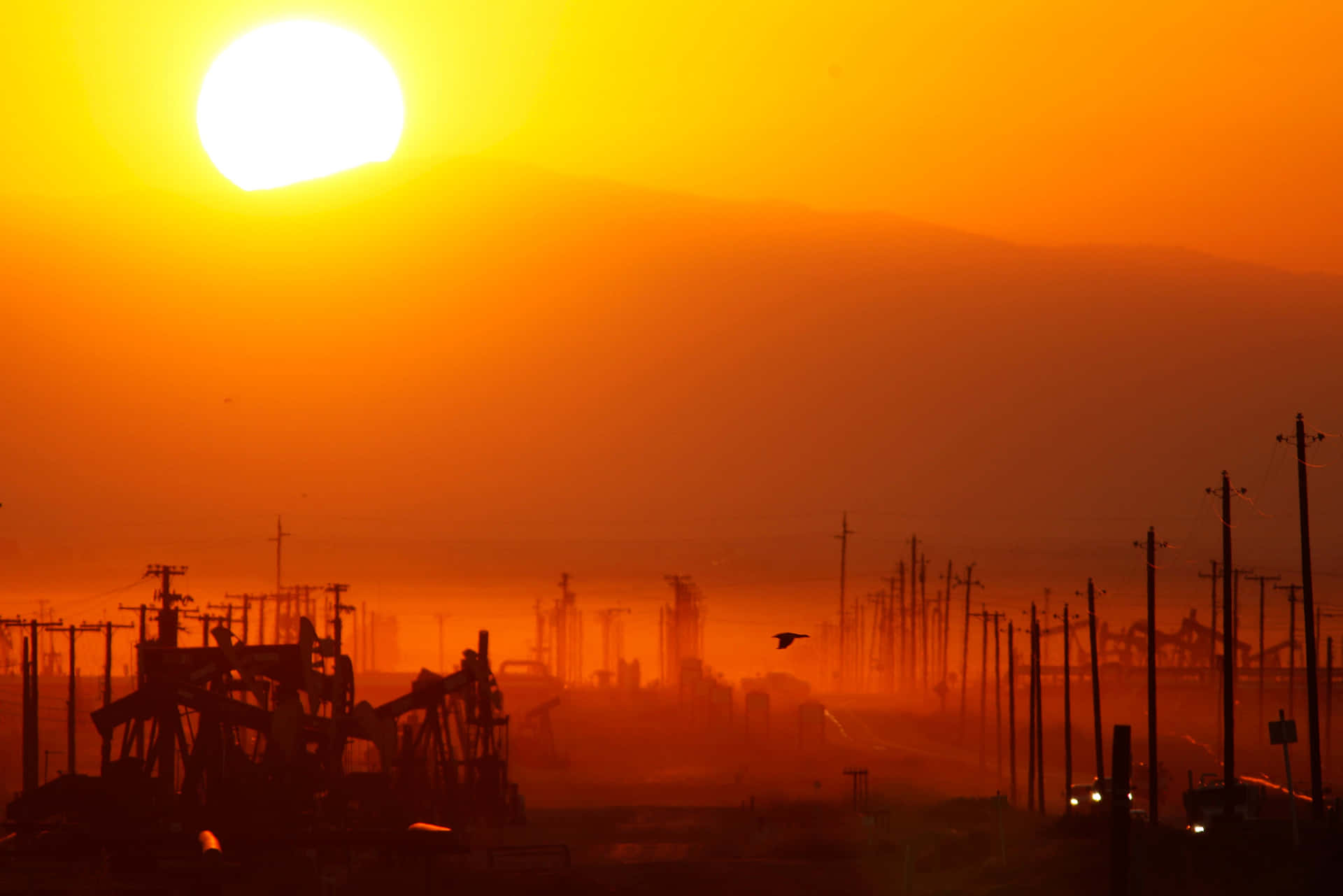 A Sunset Over A Field With Oil Pumps