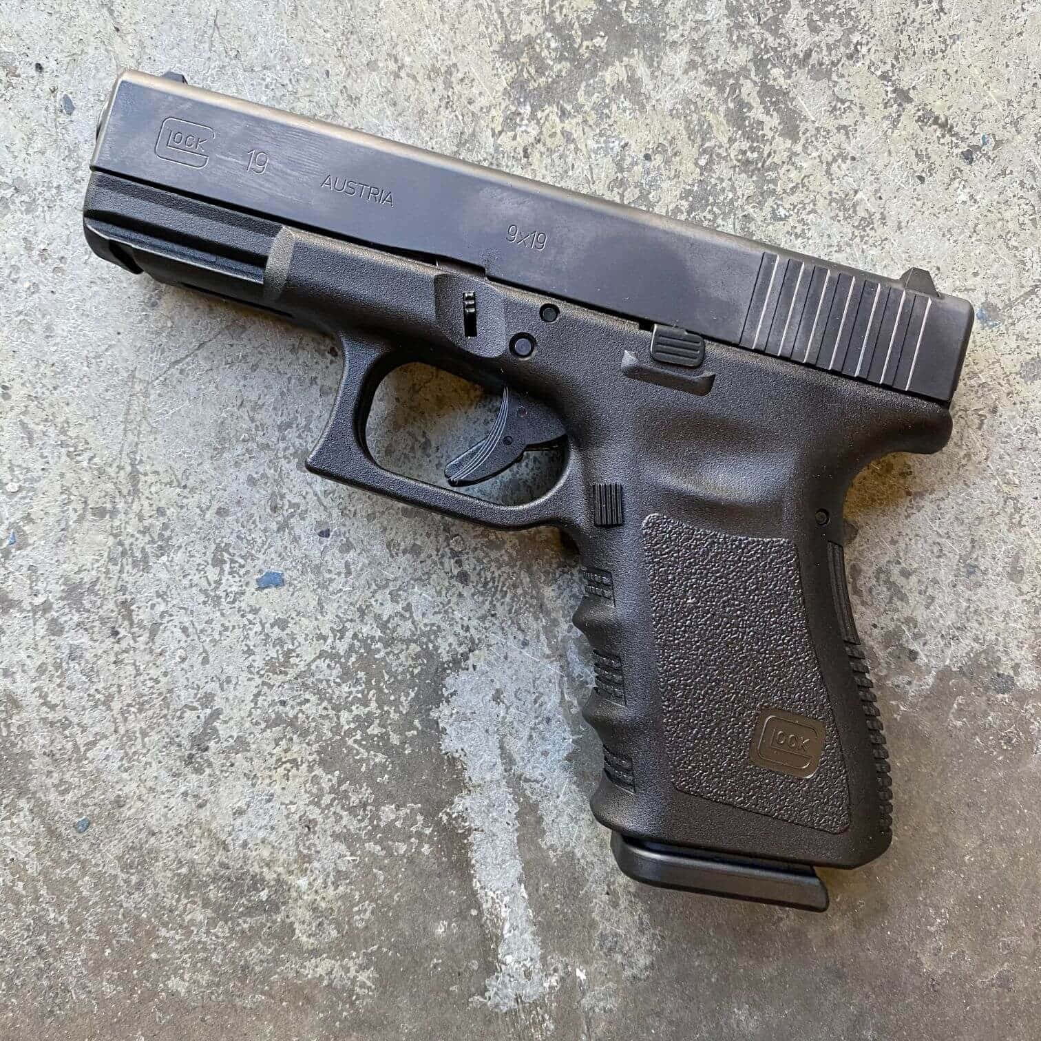 A Black Glock Handgun Is Sitting On A Concrete Surface