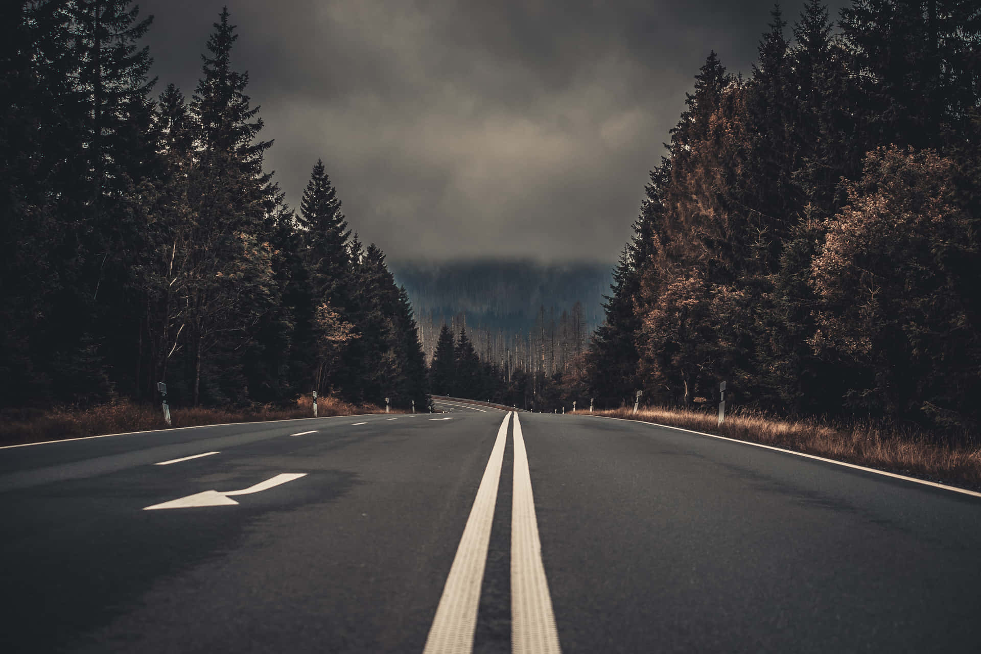 An Empty Road With Trees And Clouds Wallpaper
