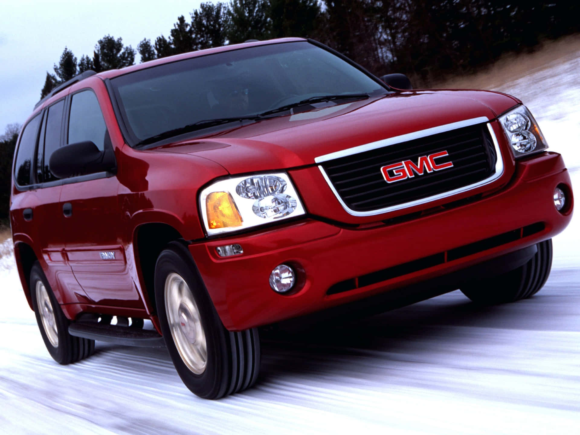 Stylish GMC Envoy in black on a scenic mountain road Wallpaper