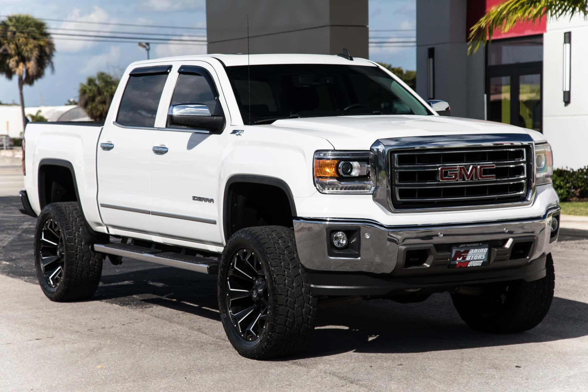 A White Gmc Sierra Parked In Front Of A Building