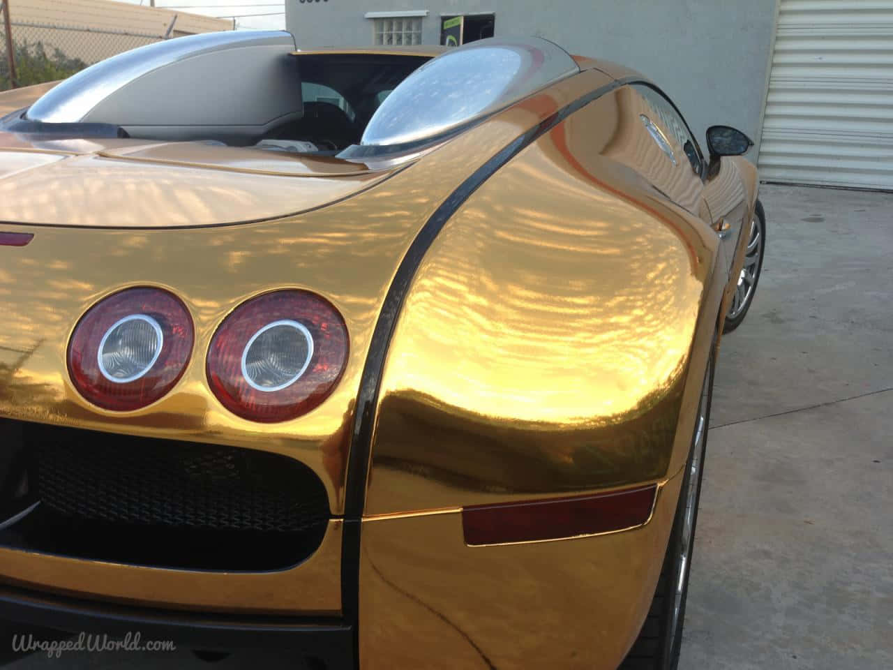 Et guld bugatti veyron parkeret i en garage fuld af eksotiske biler Wallpaper