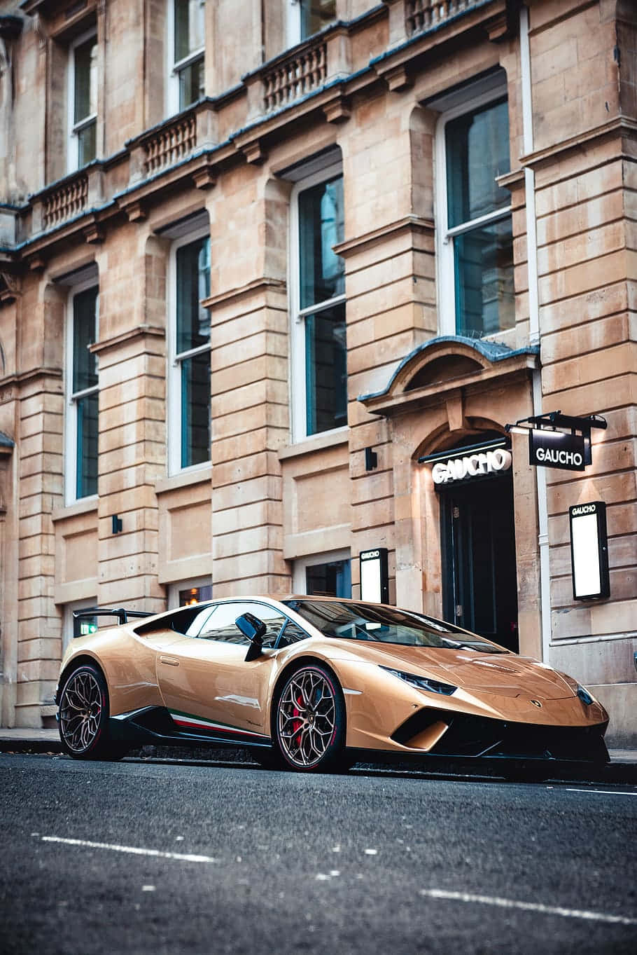 Et Guld Lamborghini Parkeret På Siden Af ​​en Gade. Wallpaper