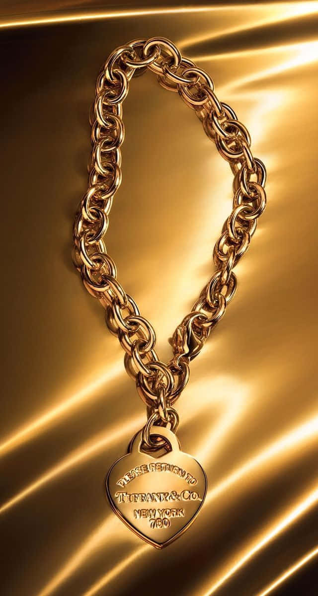 A Gold Chain Bracelet With A Heart On It Wallpaper