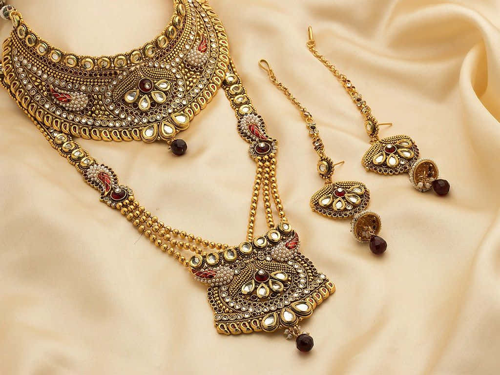 A Gold And Red Jewelry Set With A Necklace And Earrings Wallpaper