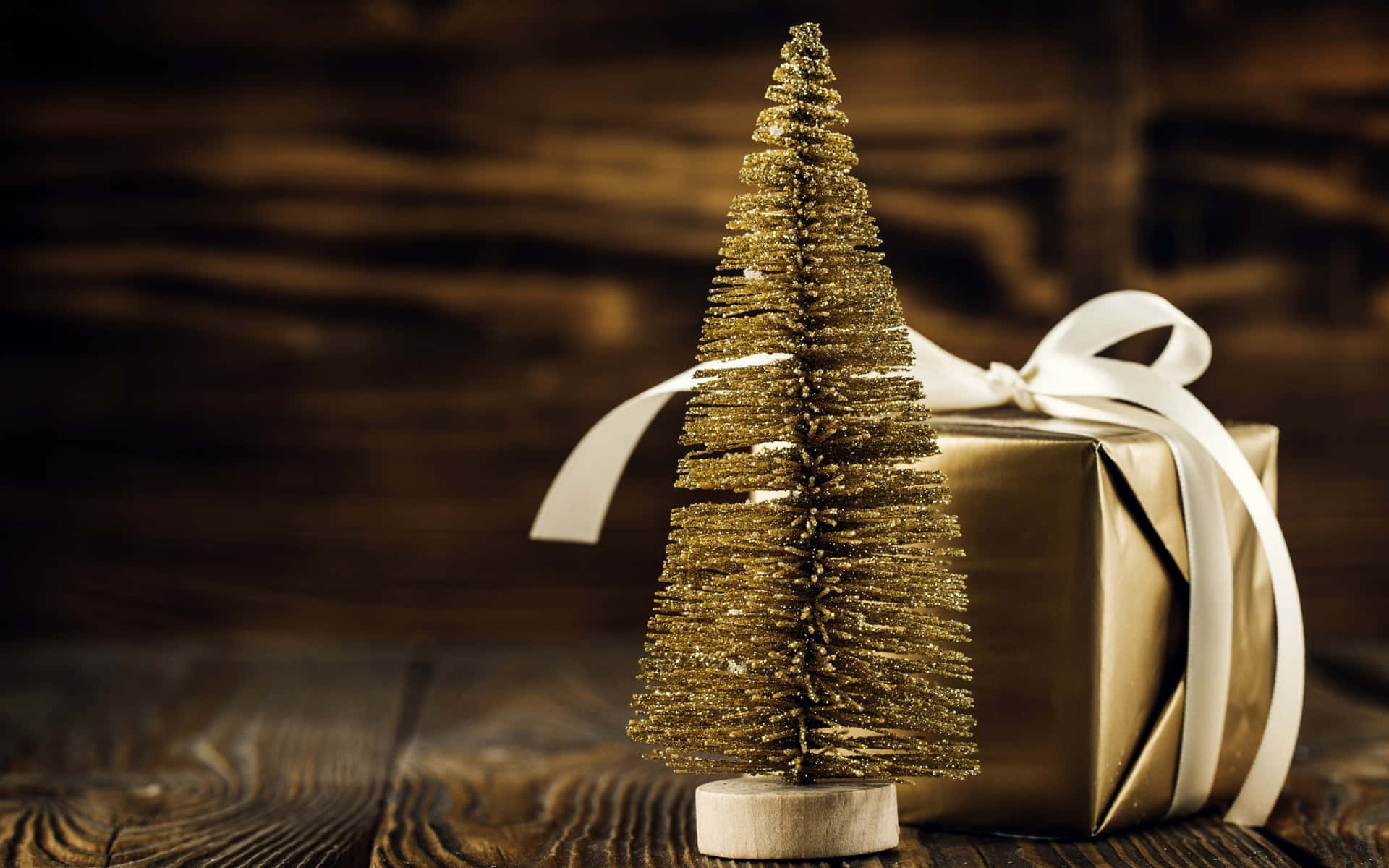 A Gold Gift Box With A Christmas Tree On A Wooden Table