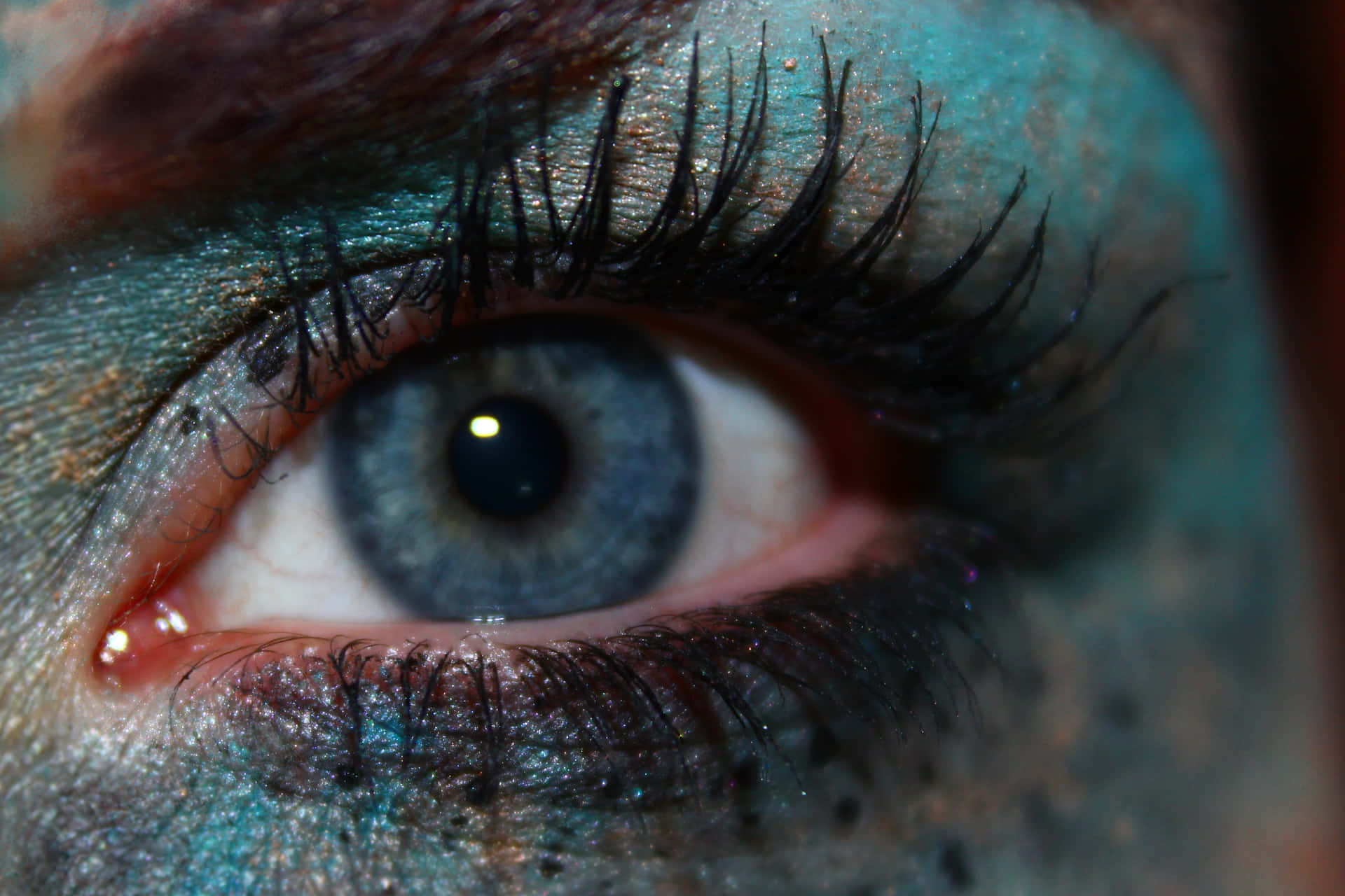A Close Up Of A Woman's Eye With Blue Makeup Wallpaper