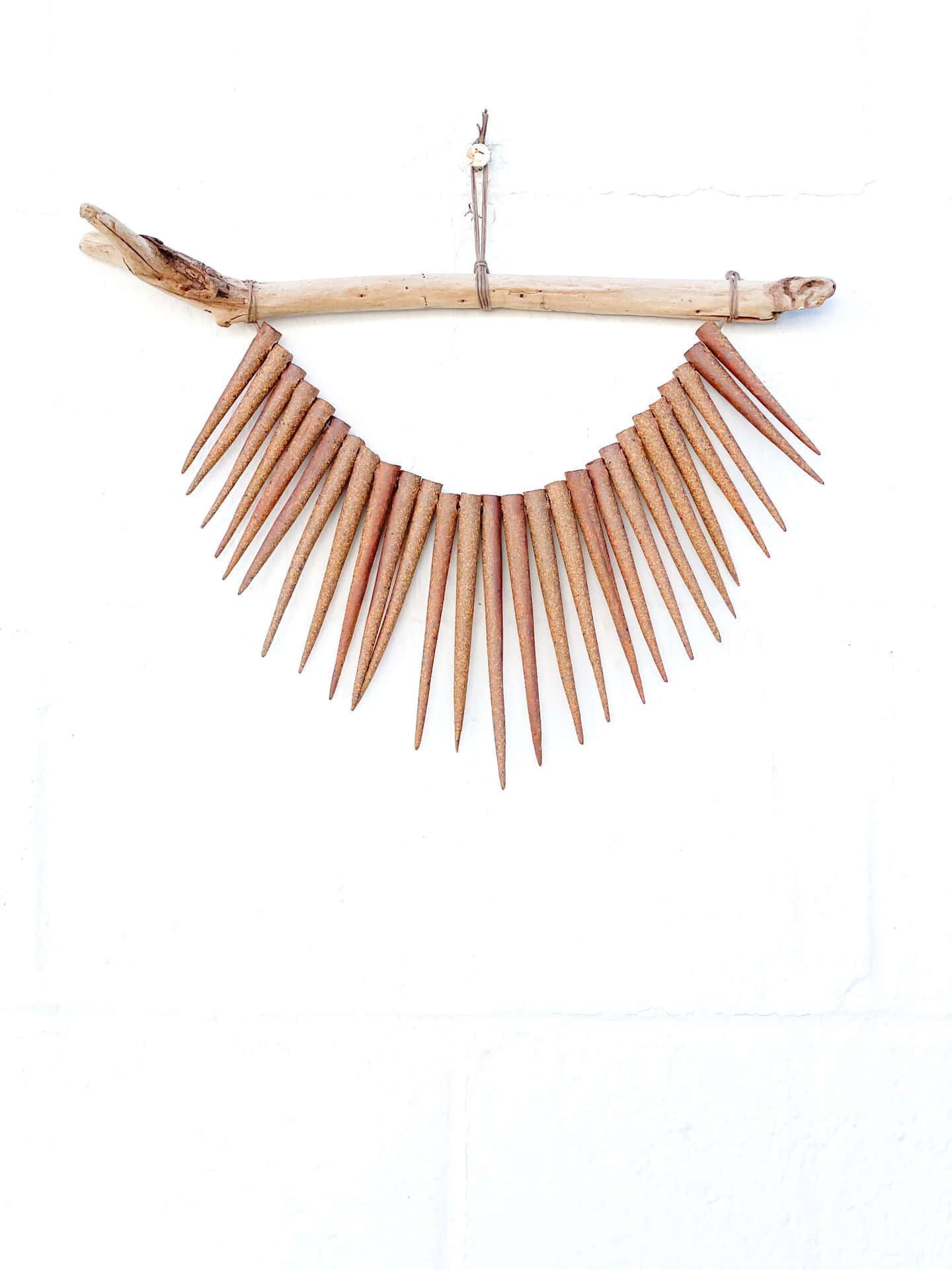 A Wooden Stick With Spikes Hanging From It Wallpaper