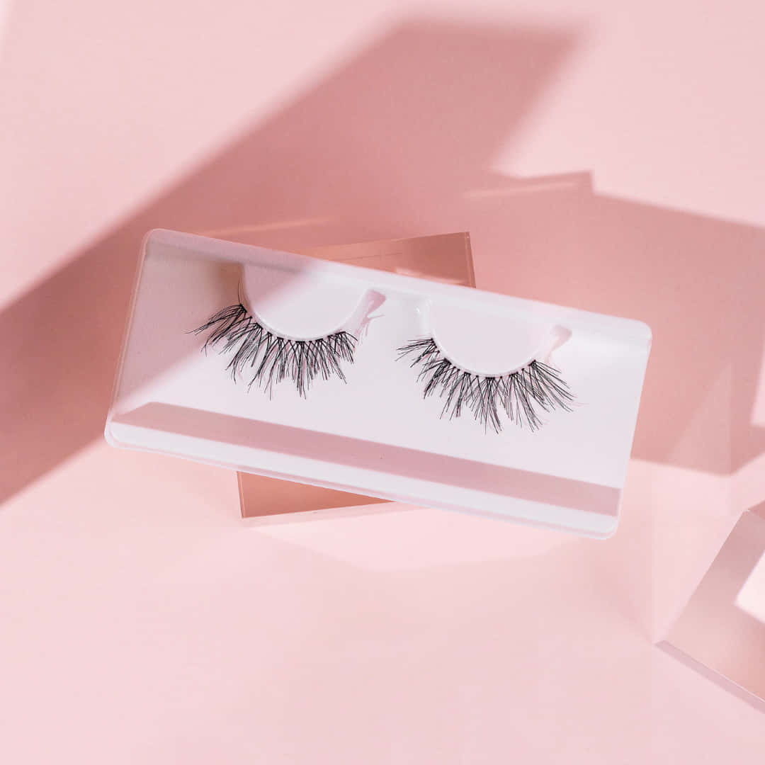 A Pair Of False Lashes On A Pink Background Wallpaper