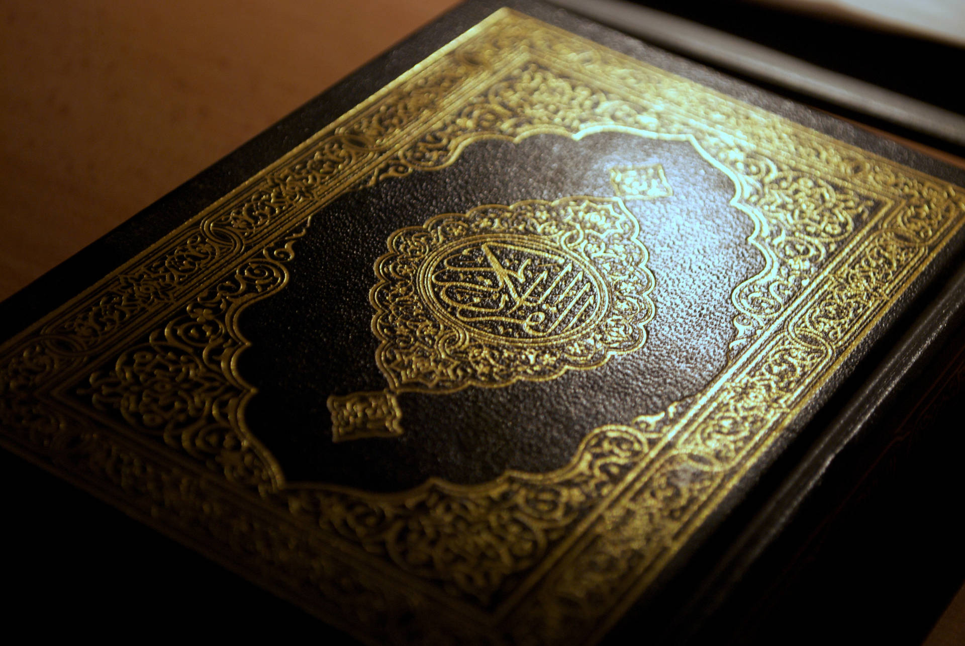 An exquisite gold Islamic book cover, beautifully decorated with intricate artwork. Wallpaper