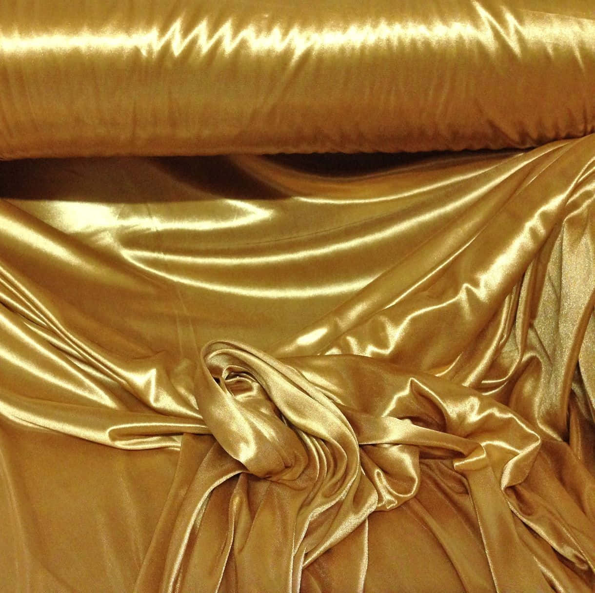 Et guld satin stof ligger på et bord. Wallpaper