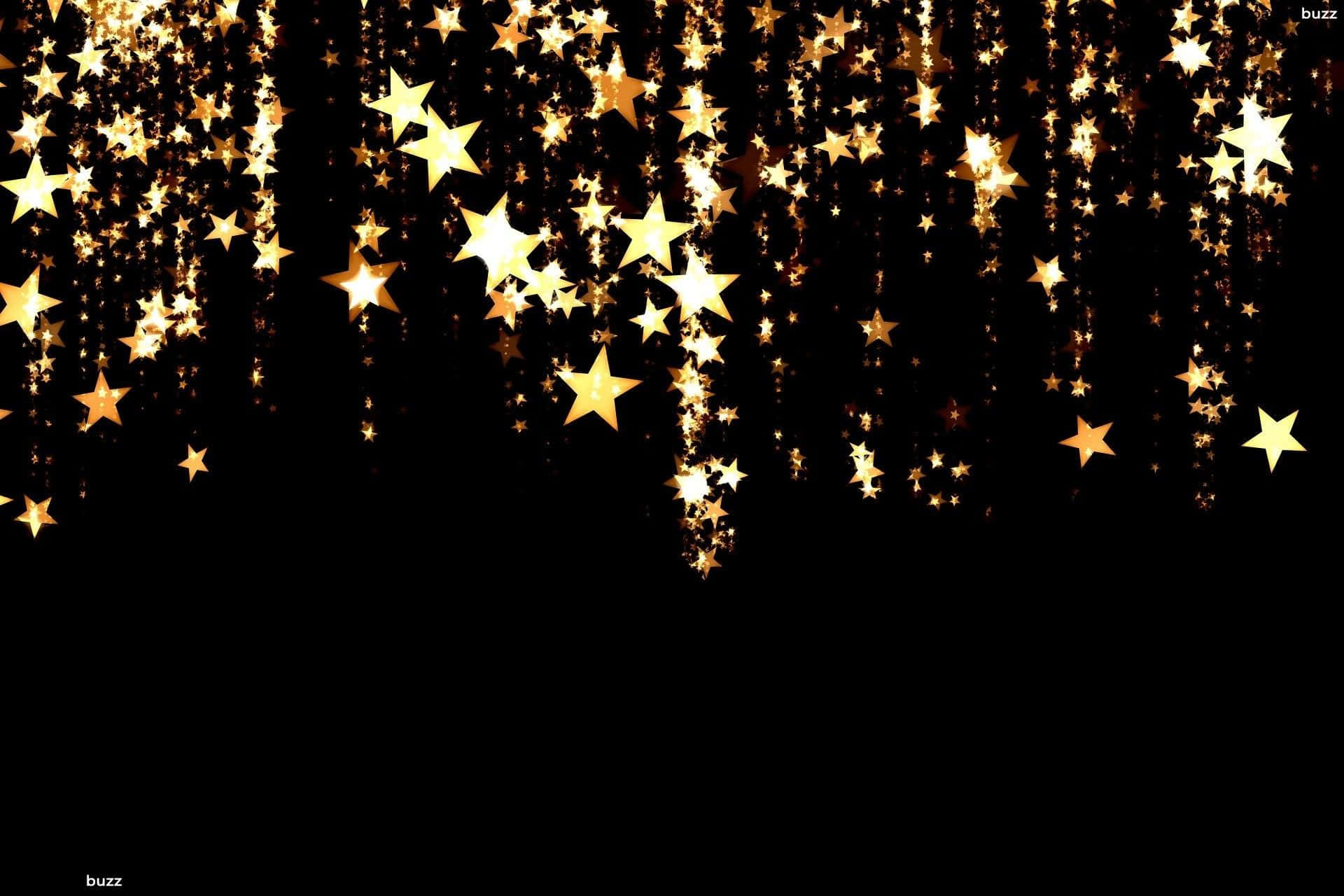 A rain of golden stars cascades through the night sky, shining bright in the darkness. Wallpaper