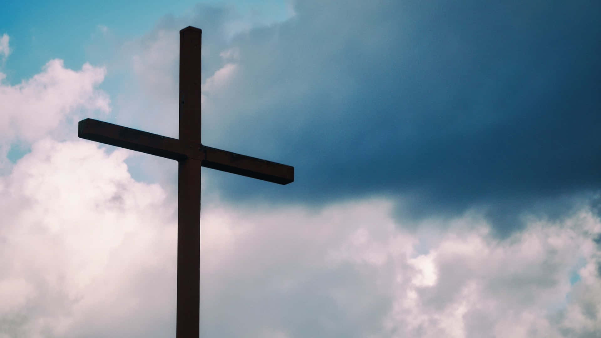 A Cross Is Shown Against A Cloudy Sky