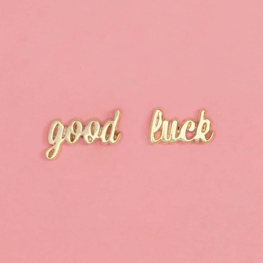 Two Gold Stud Earrings With The Words Good Luck