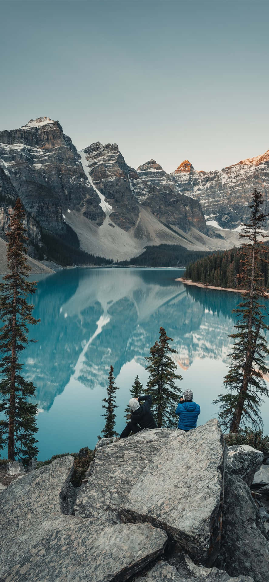Unhombre Está Sentado En Una Roca Observando Un Lago. Fondo de pantalla