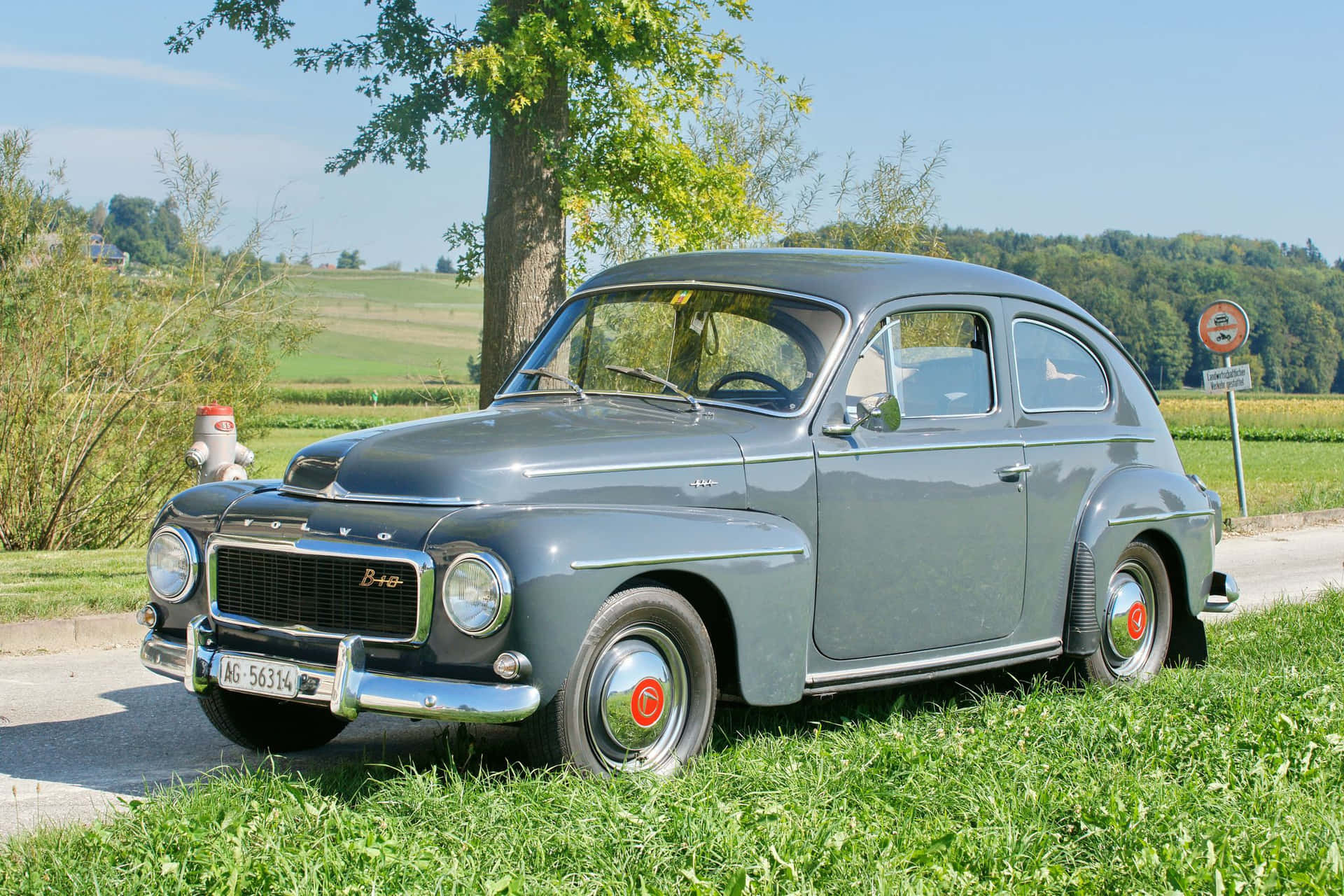 Graceful Vintage Charm - Volvo Pv544 Parked On A Road Wallpaper