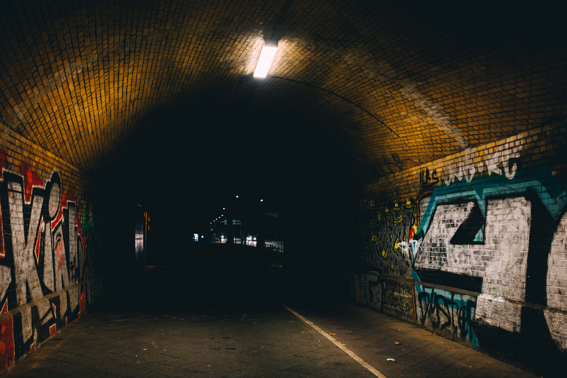Graffiti Adorned Urban Tunnel At Night Wallpaper