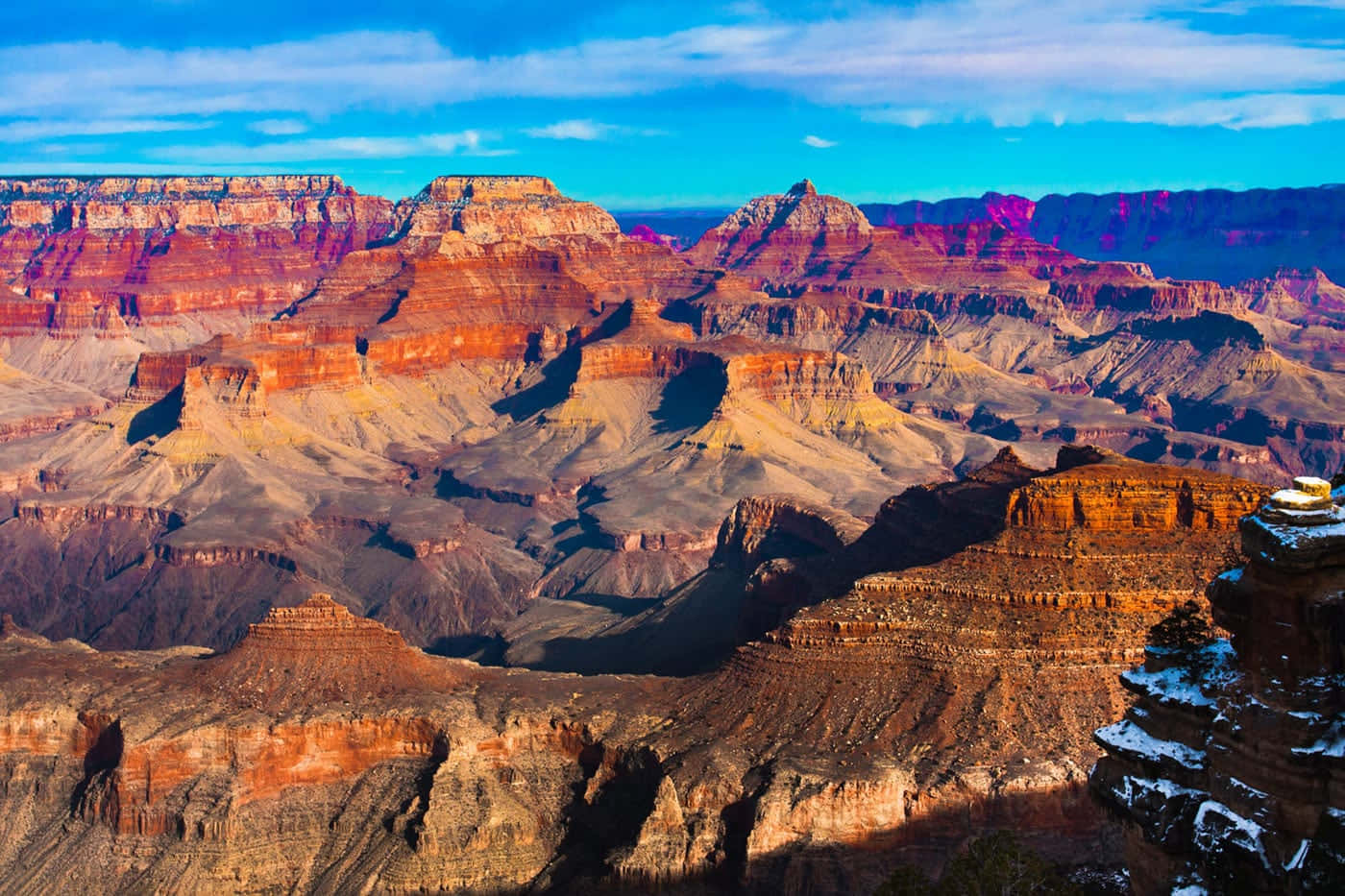 The Grand Canyon's majestic, towering rocks shine in an orange and pink sunset.