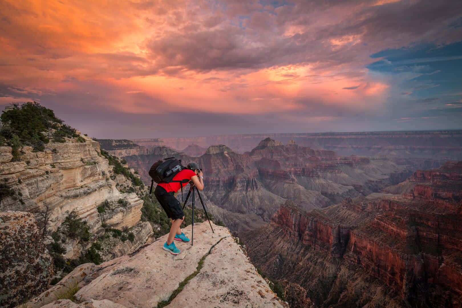 A Man Standing On A Cliff Overlooking The Grand Canyon