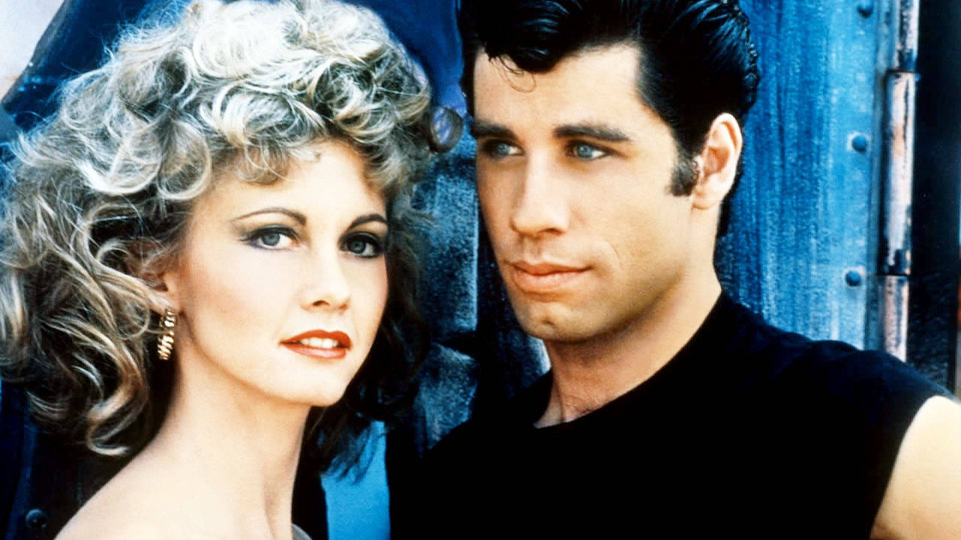 Grease John And Olivia Standing Together Background