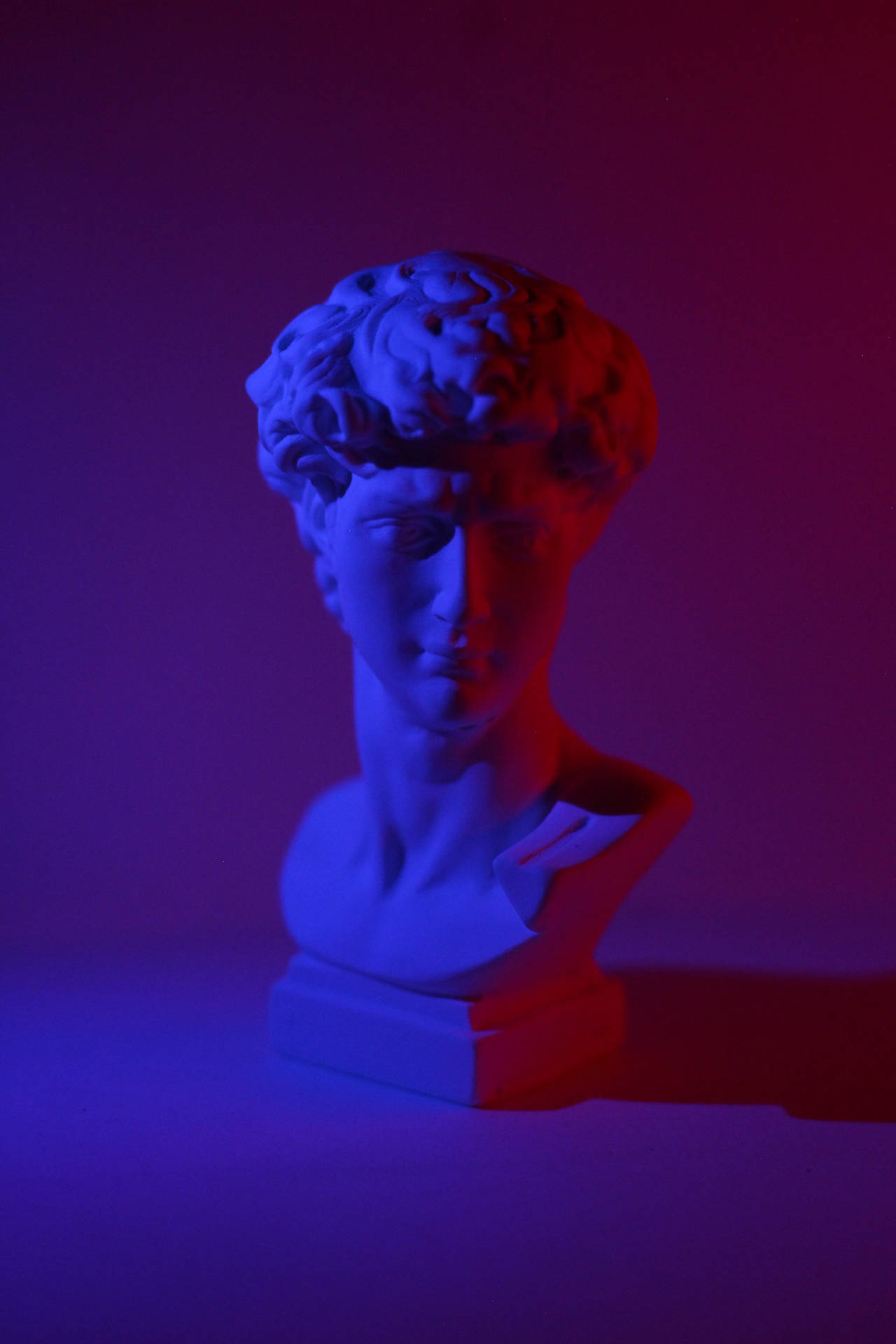 A Bust Of David With Blue And Red Lights Wallpaper