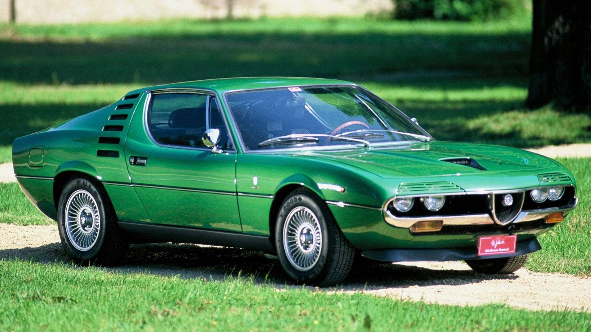 Enjoy the fresh air and high speed in the Green Alfa Romeo Montreal Wallpaper