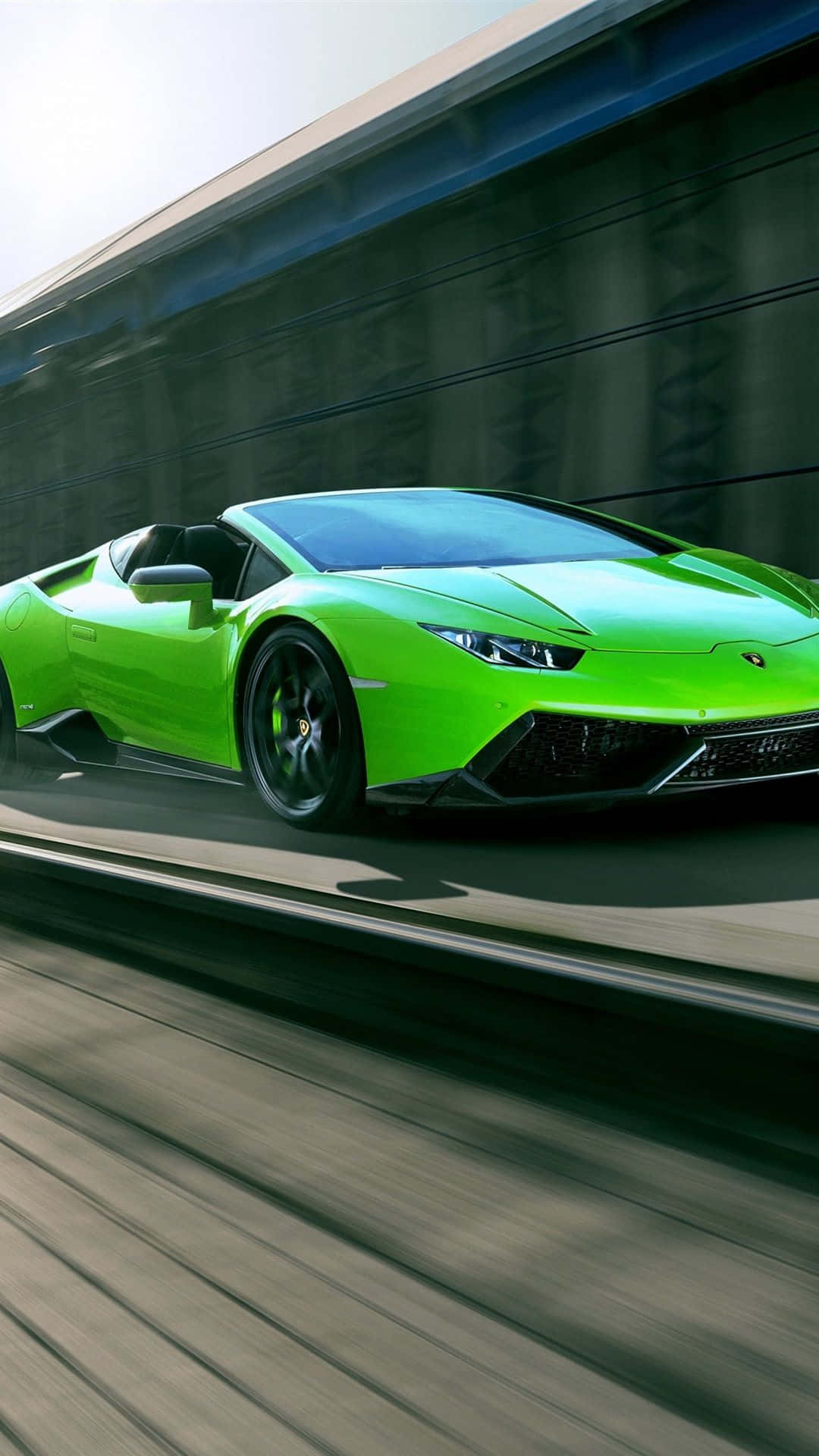 A Green Sports Car Is Driving Down A Track Wallpaper