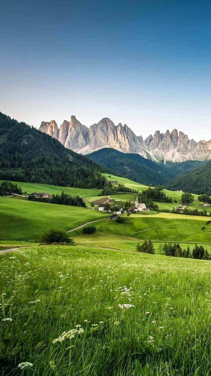 En grøn mark med bjerge i baggrunden Wallpaper