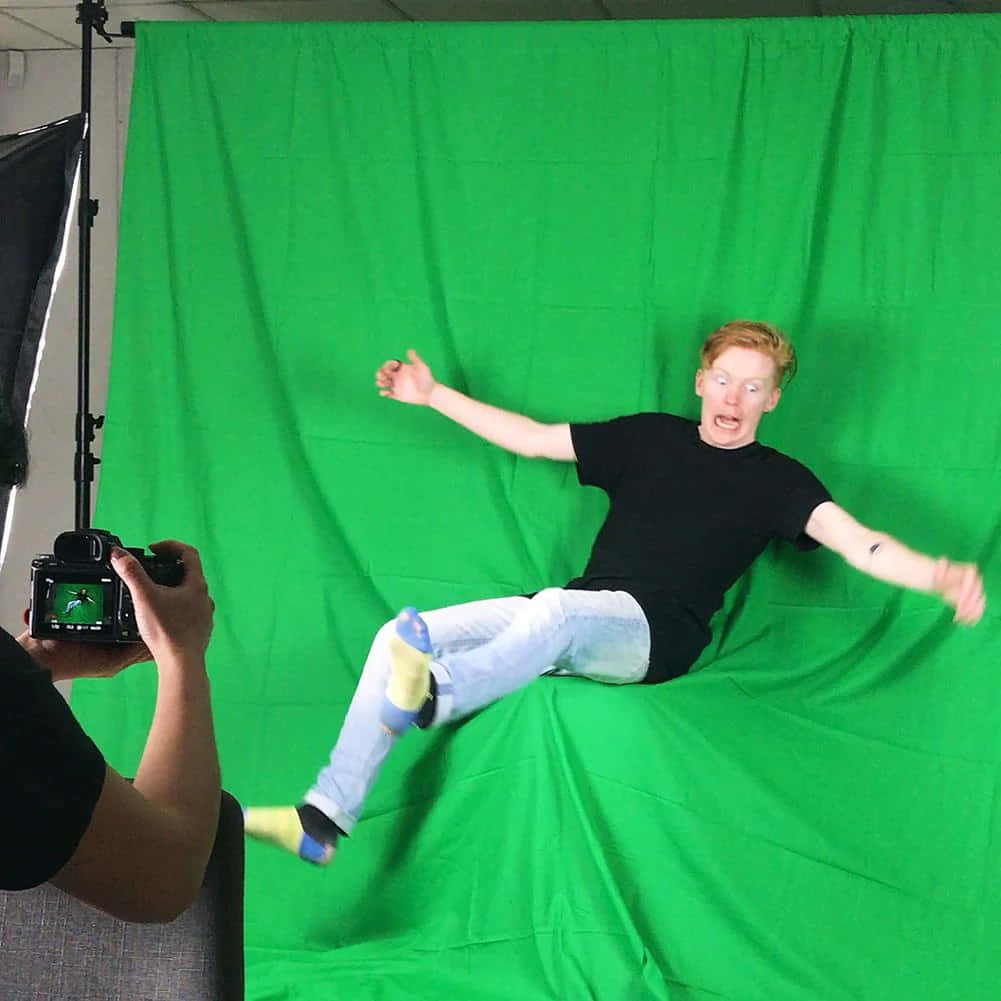 a man is laying on a green screen while being photographed Wallpaper