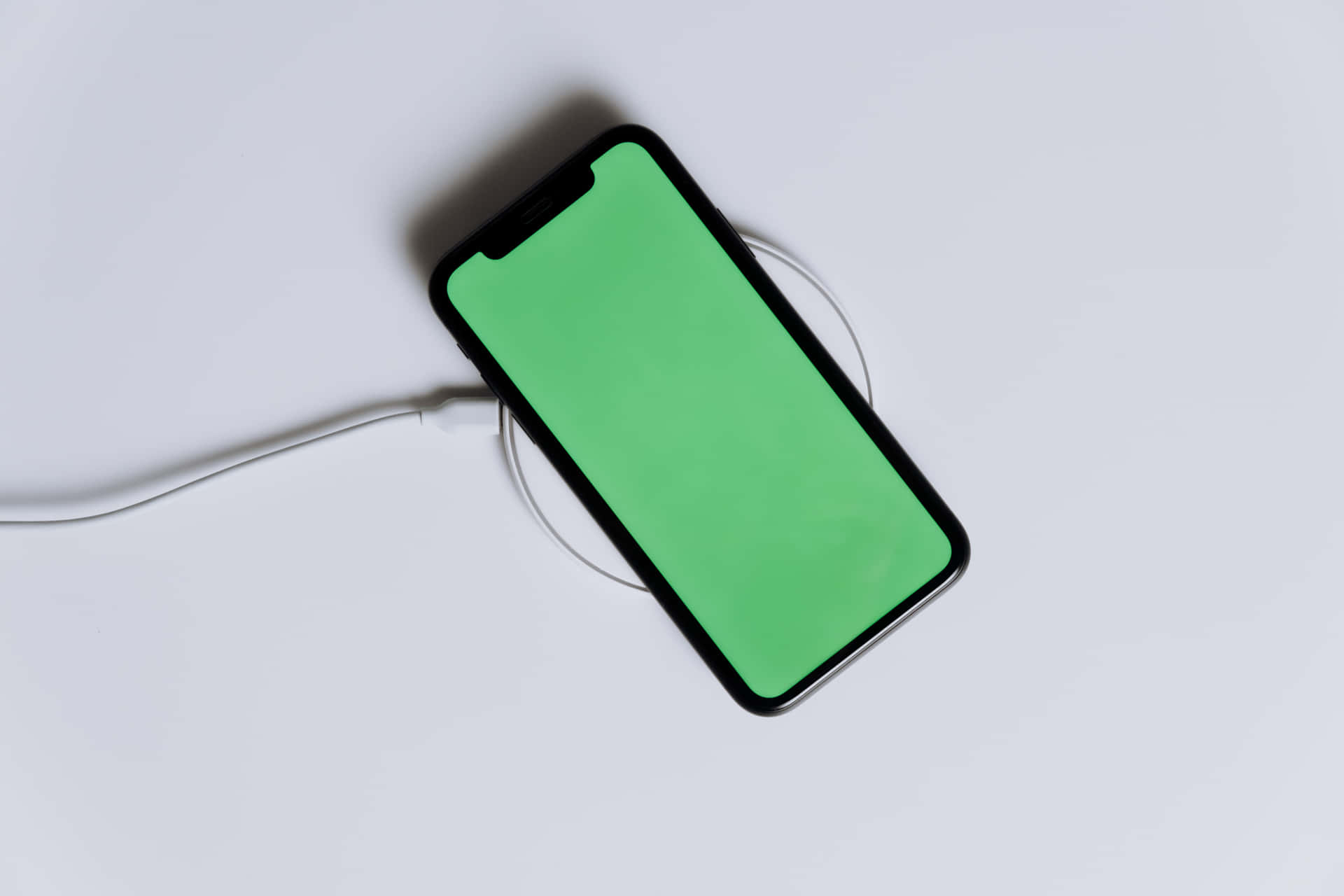 an iphone x is charging with a green screen
