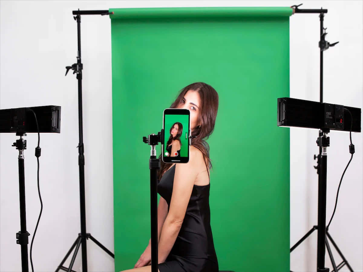 a woman is posing in front of a green screen