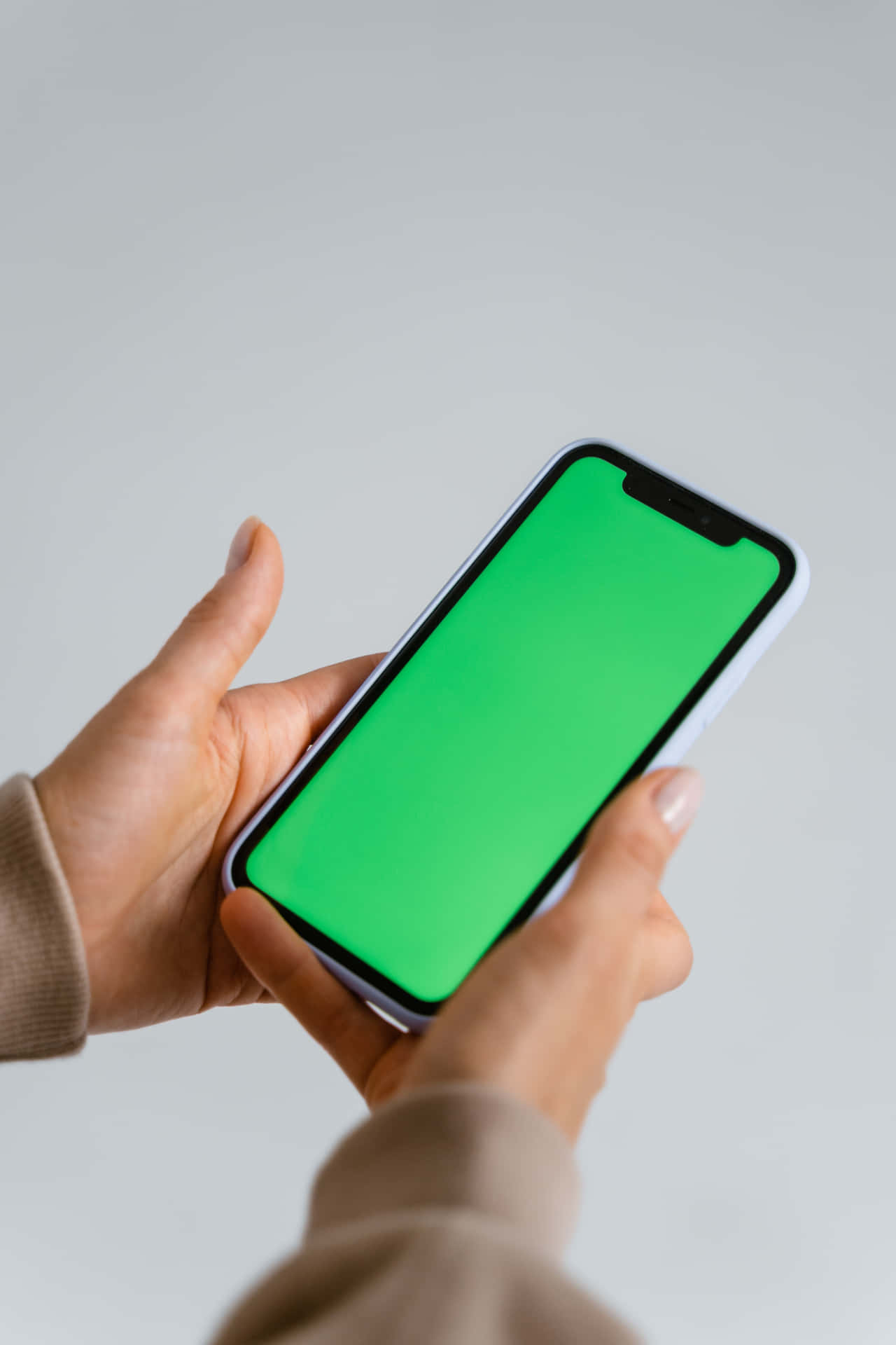 woman holding green screen iphone xr smartphone on gray background