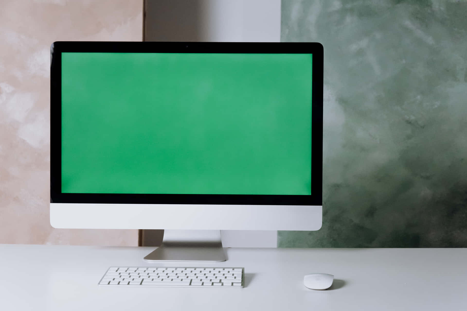 A Computer With A Green Screen On A White Desk