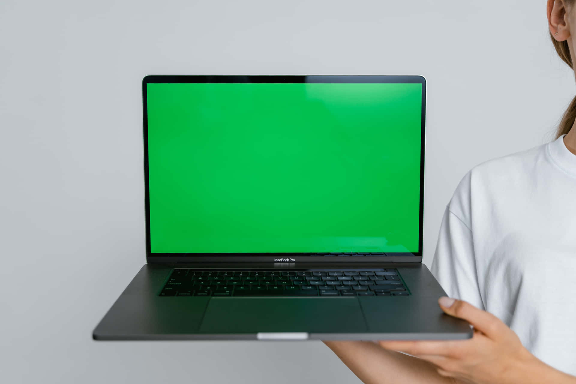 a woman holding a laptop with a green screen
