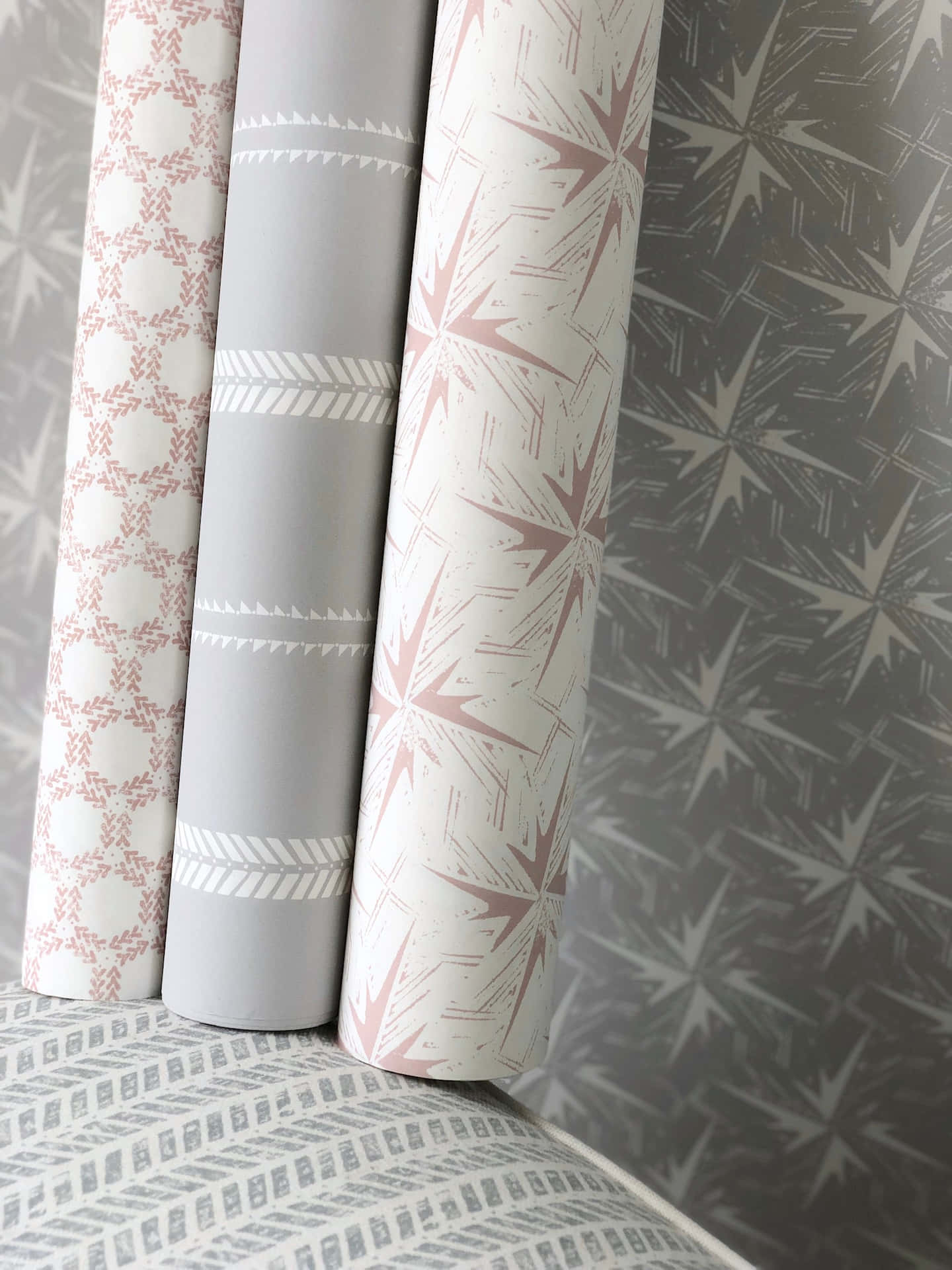 A Stack Of Pink And Grey Wallpapers On A Bed Wallpaper
