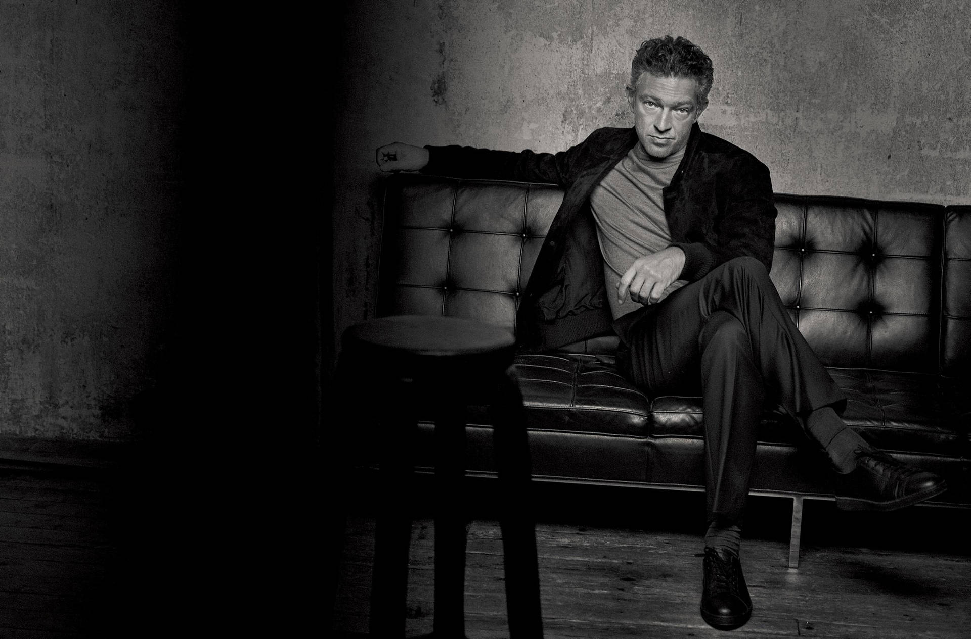 Greyscale Vincent Cassel Sitting On Couch Wallpaper
