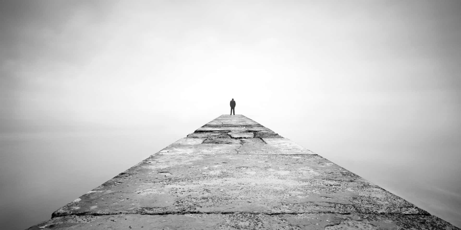 A Man Standing On A Pier In The Fog